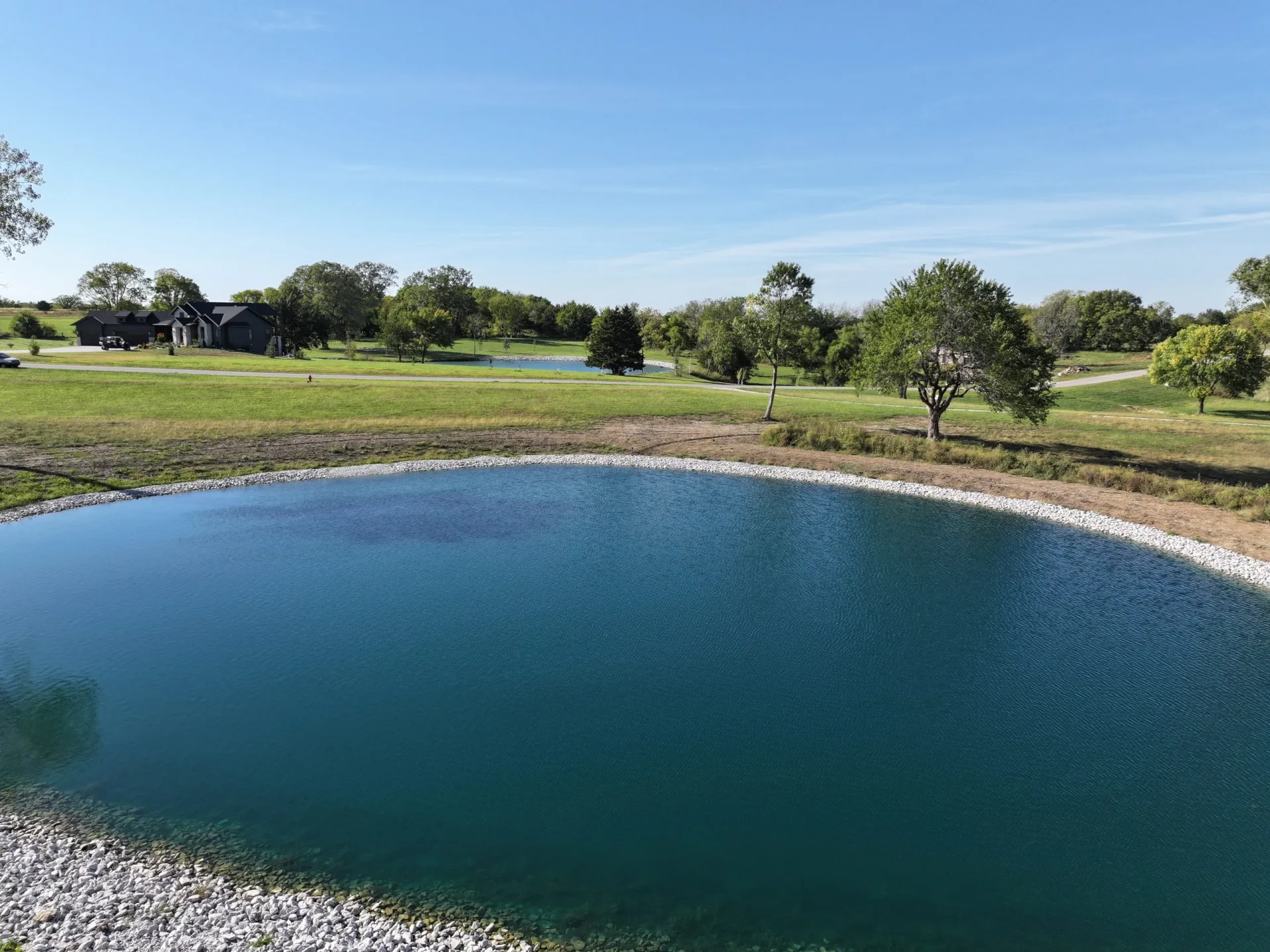 Better Way Land Management LLC completed pond installation with white rock border edging on rural property in OH