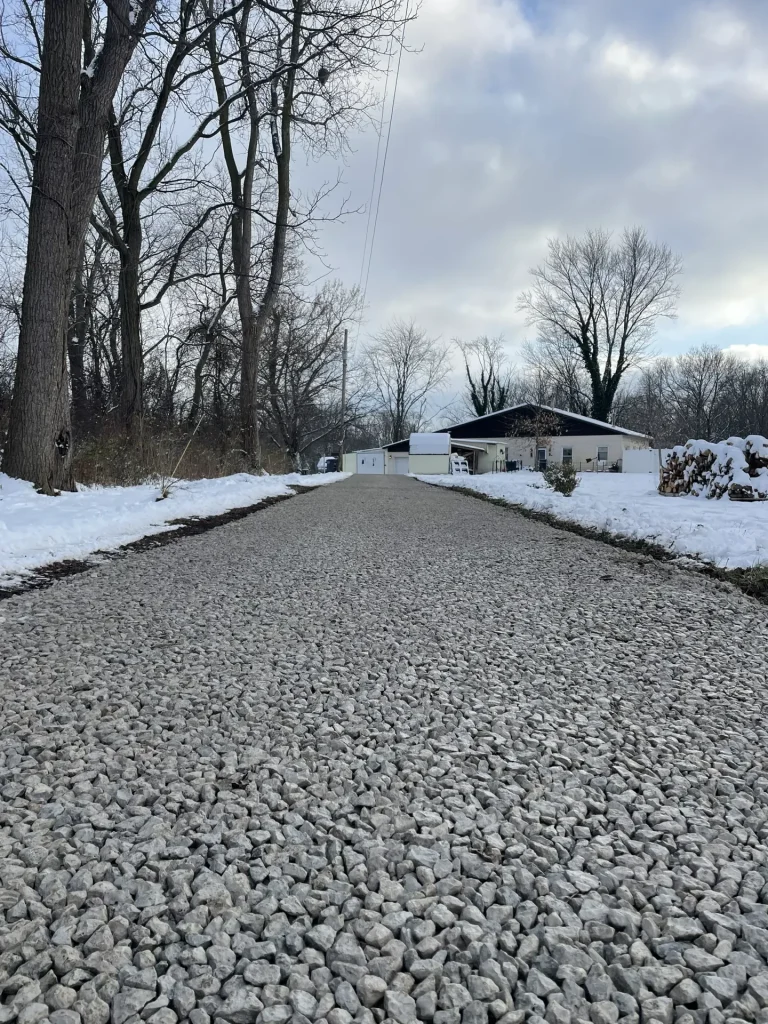 Better Way Land Management freshly installed gravel driveway leading to rural residential property with snow-covered yard in Ohio winter setting