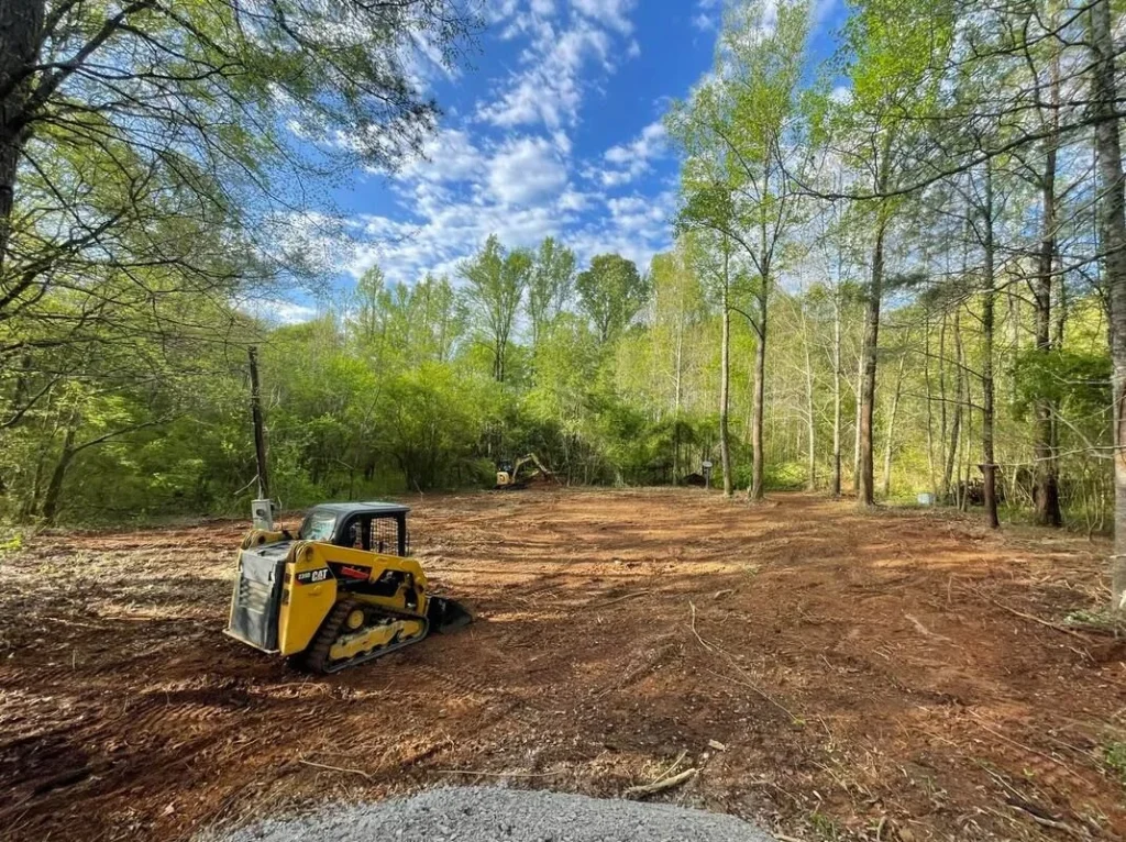 Better Way Land Management LLC compact track loader clearing wooded property with excavator working in background on freshly cleared land
