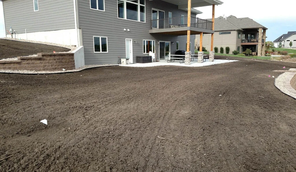 Better Way Land Management freshly graded topsoil backyard with concrete patio and retaining wall residential property Ohio